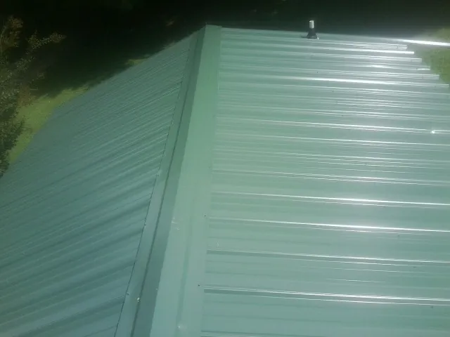 New green metal panels meeting at the ridge of a roof — Flat Roof Repair work by our crew in Eminence