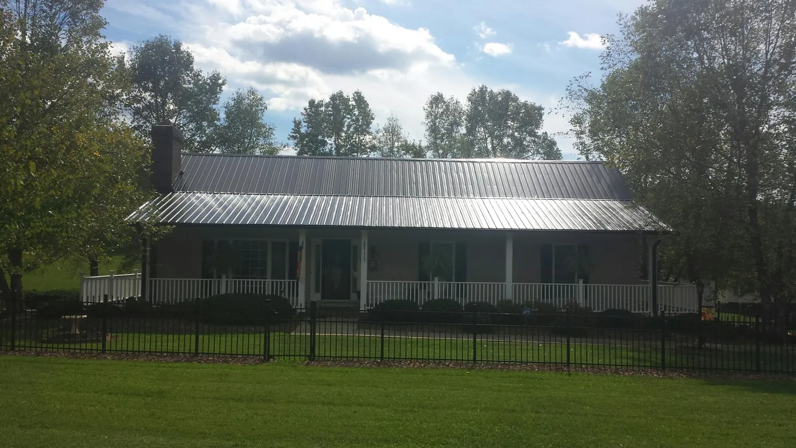 Gray metal roof on a brick ranch with a full width front porch — Gutter Guard Installation work by our crew in Eminence