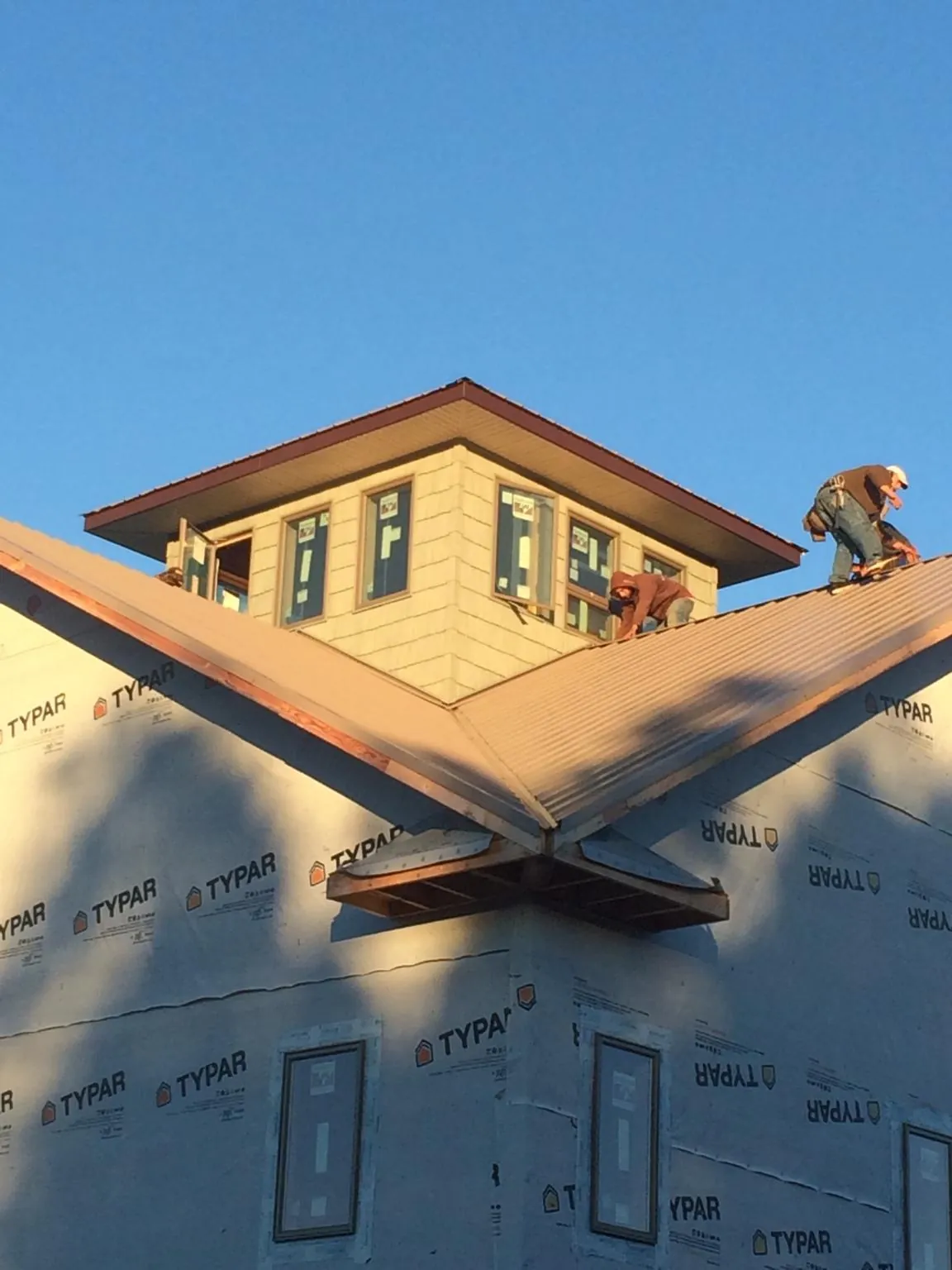 Roofers working around a rooftop cupola on a new metal roof at sunset — Roof Waterproofing in Eminence by Roofing Brothers